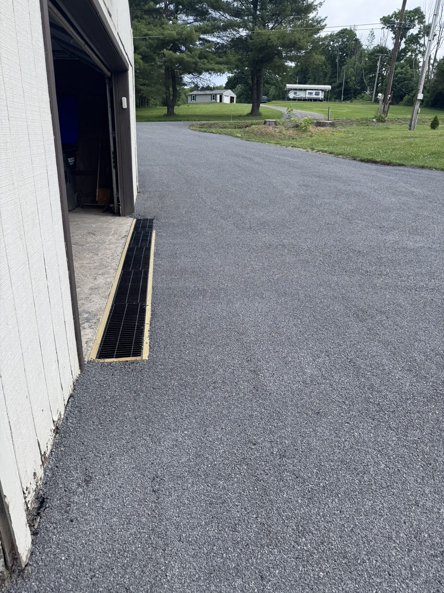 Finished stone and oil driveway running alongside a barn with a new drainage channel.