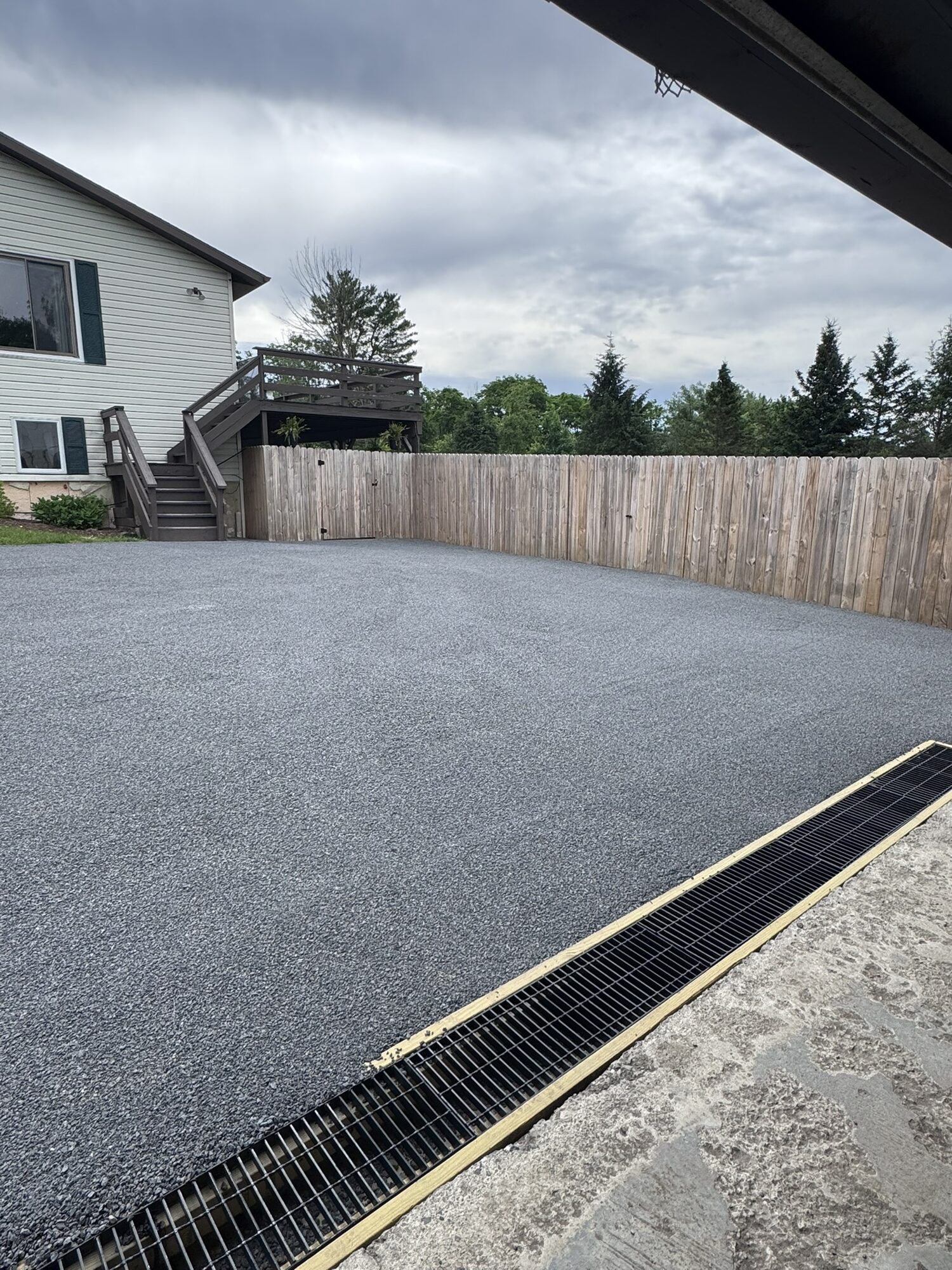 Newly resurfaced chip seal driveway with a channel drain installed at the garage.