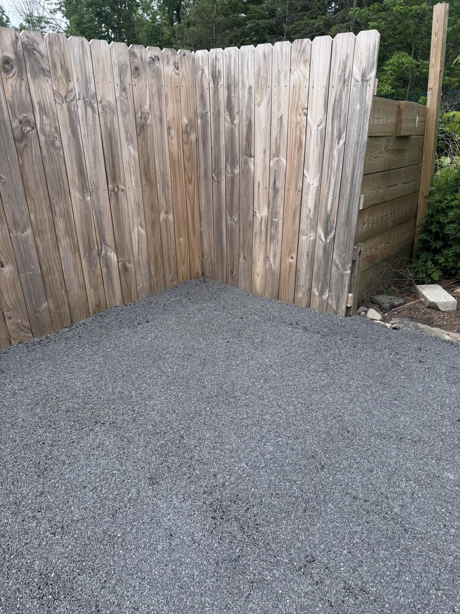 Clean, freshly sealed driveway surface in the fenced corner after Rock Solid stone and oil work.