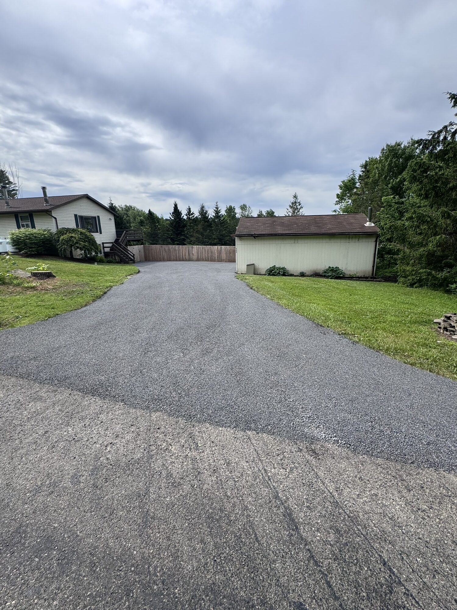 Full-length view of a newly finished stone and oil driveway leading out to the road.